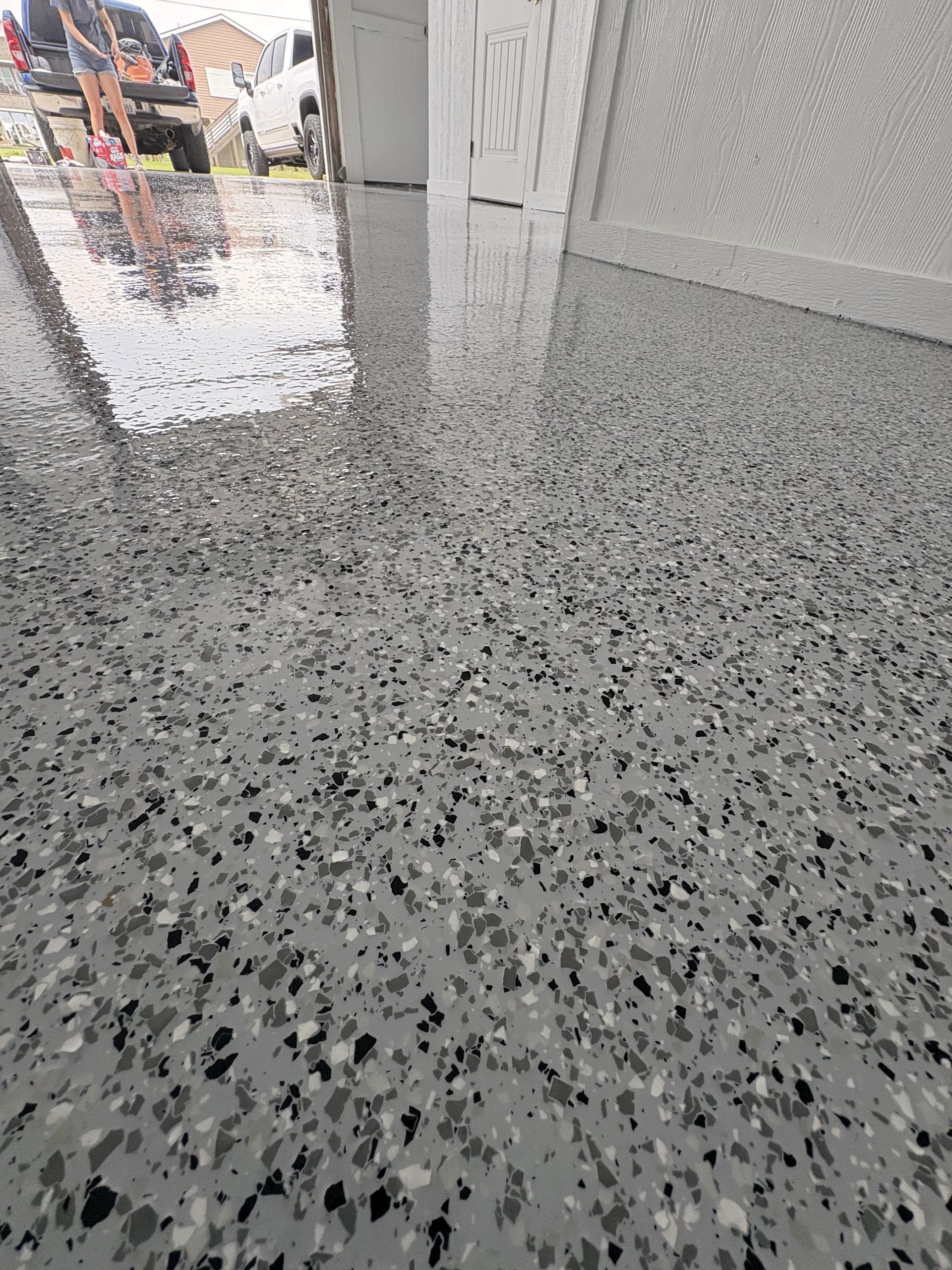 Epoxy garage floor speckled with gray, black, and white chips; glossy finish.