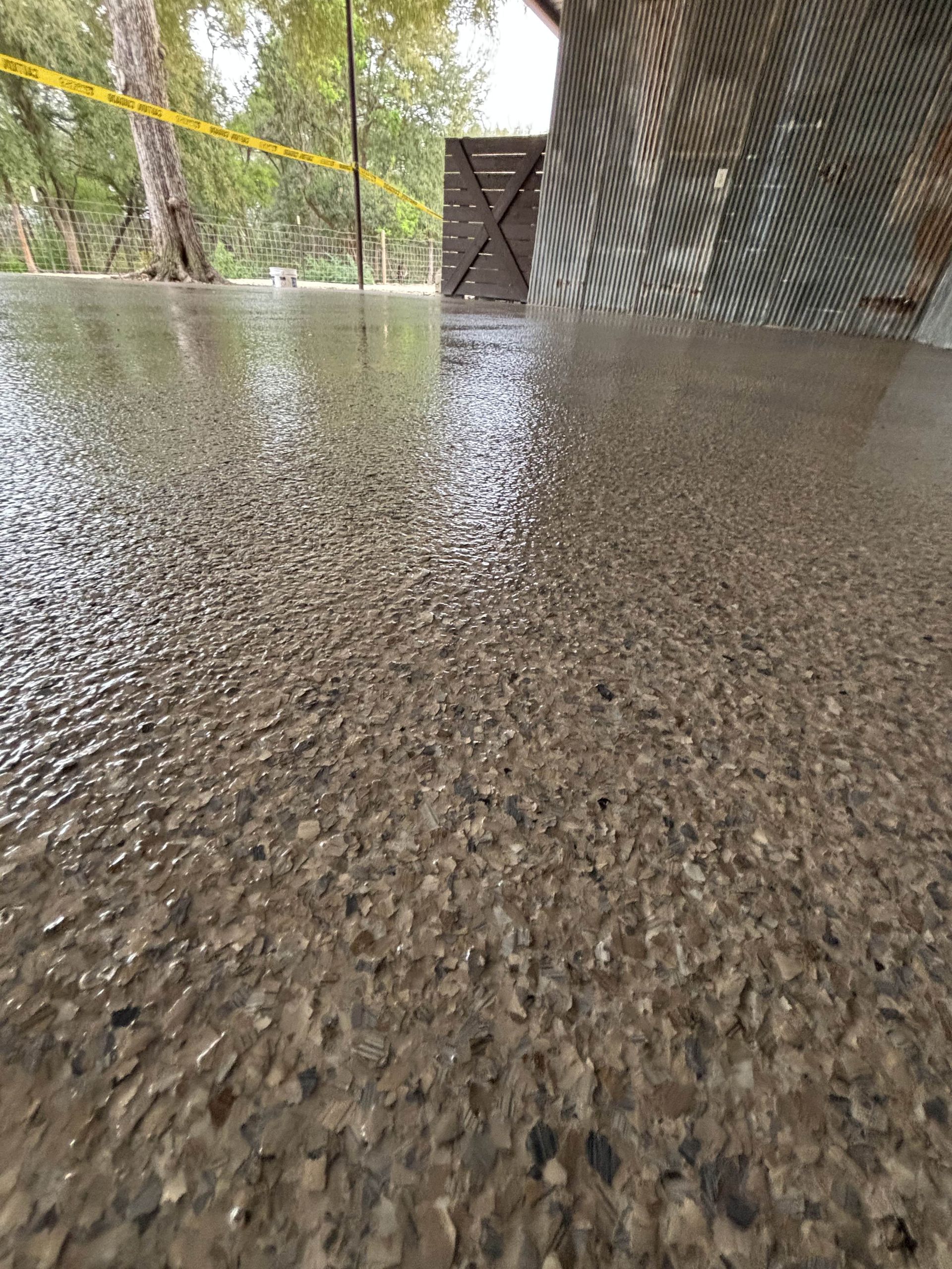 Wet, polished concrete floor with a textured surface, possibly outdoors.