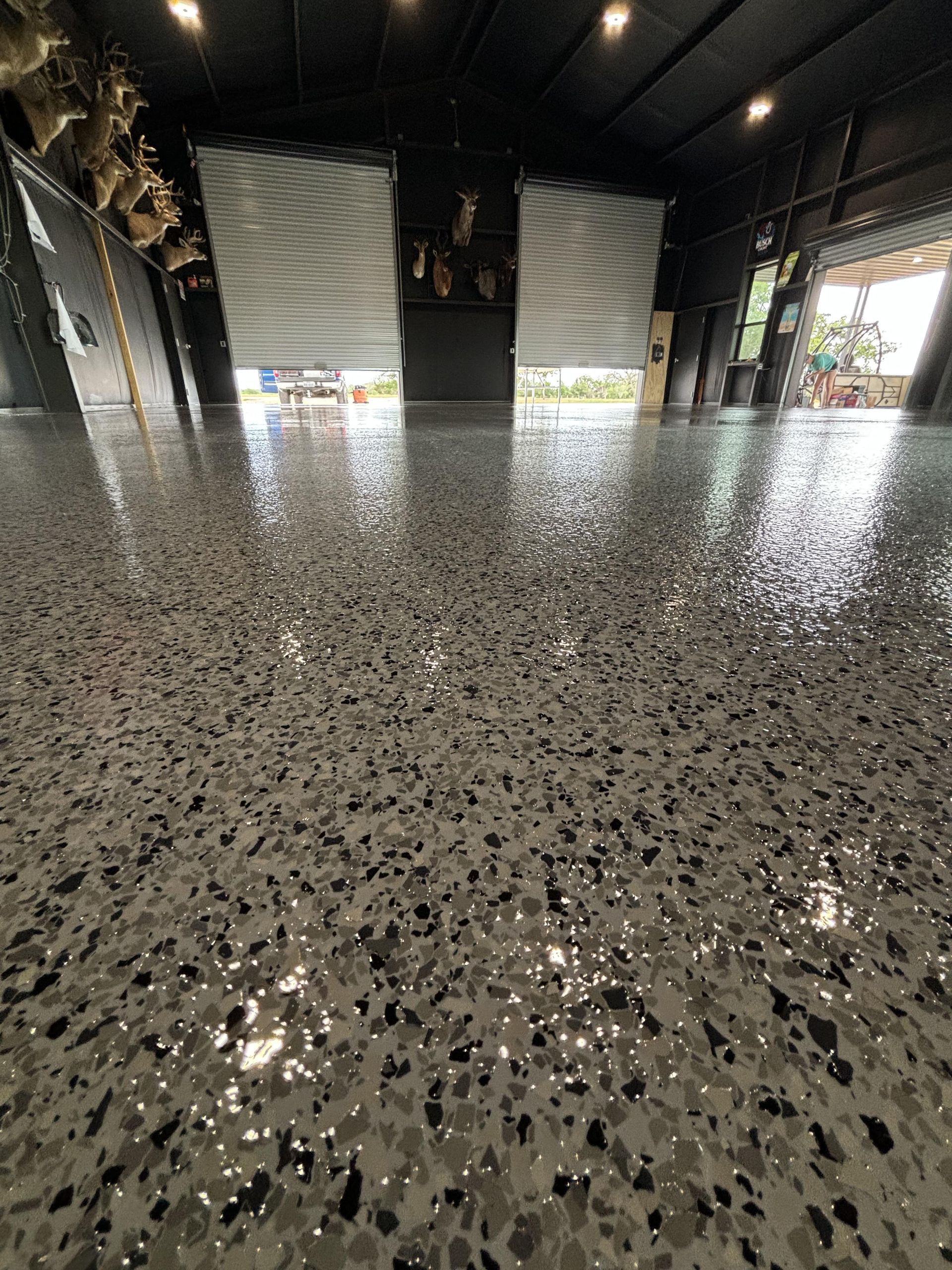 Glossy speckled concrete floor inside a dark building. Two closed window coverings are visible.