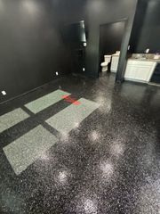 Black room with glitter-covered floor, bathroom visible in the background, and sunlight shining in.