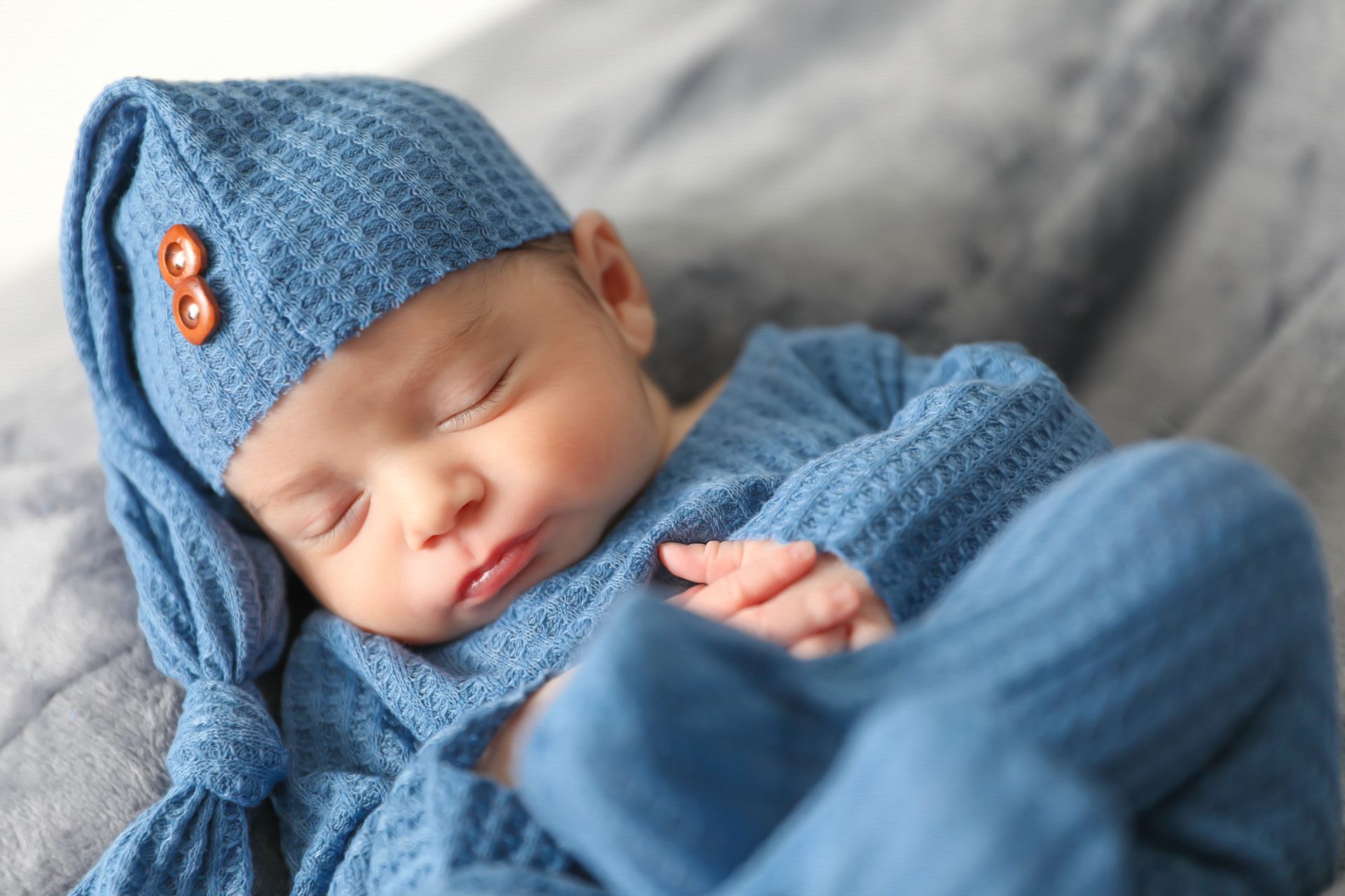 Sleeping newborn baby boy wearing a blue knit hat
