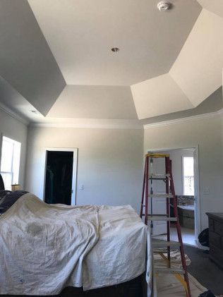 Bedroom ceiling with geometric design, ladder, and a covered bed. Painted in white and light gray tones.