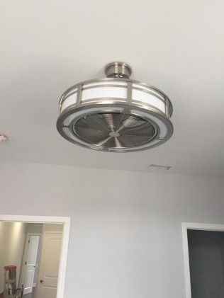 Ceiling fan with circular light fixture, silver finish. Installed on a white ceiling above a room with light gray walls.