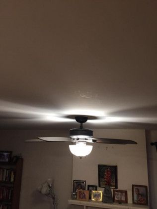 Ceiling fan with light illuminating the ceiling and casting shadows.