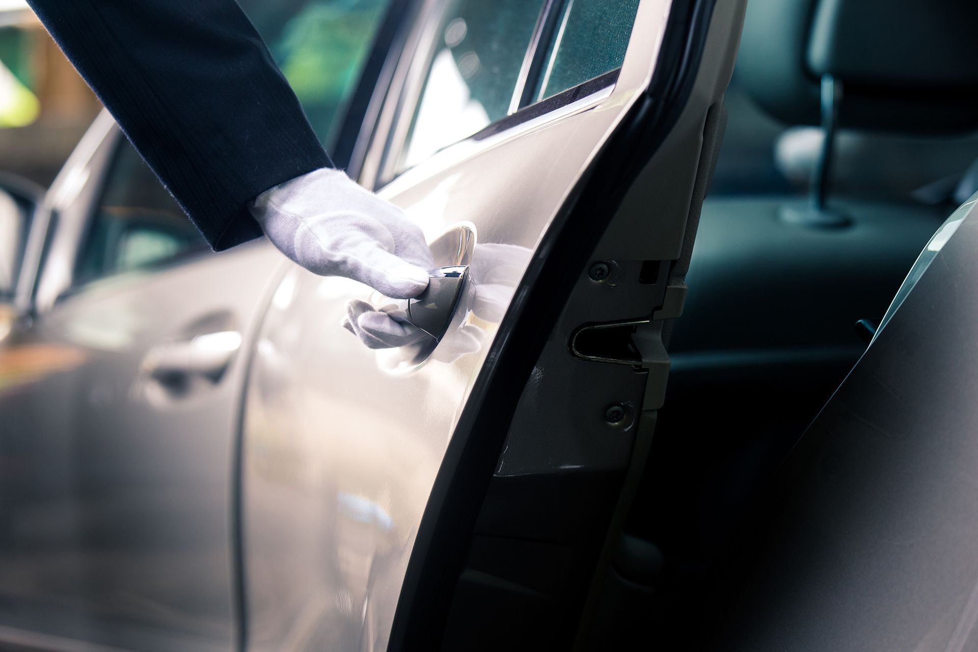 Chauffeur in white gloves opens a car door.