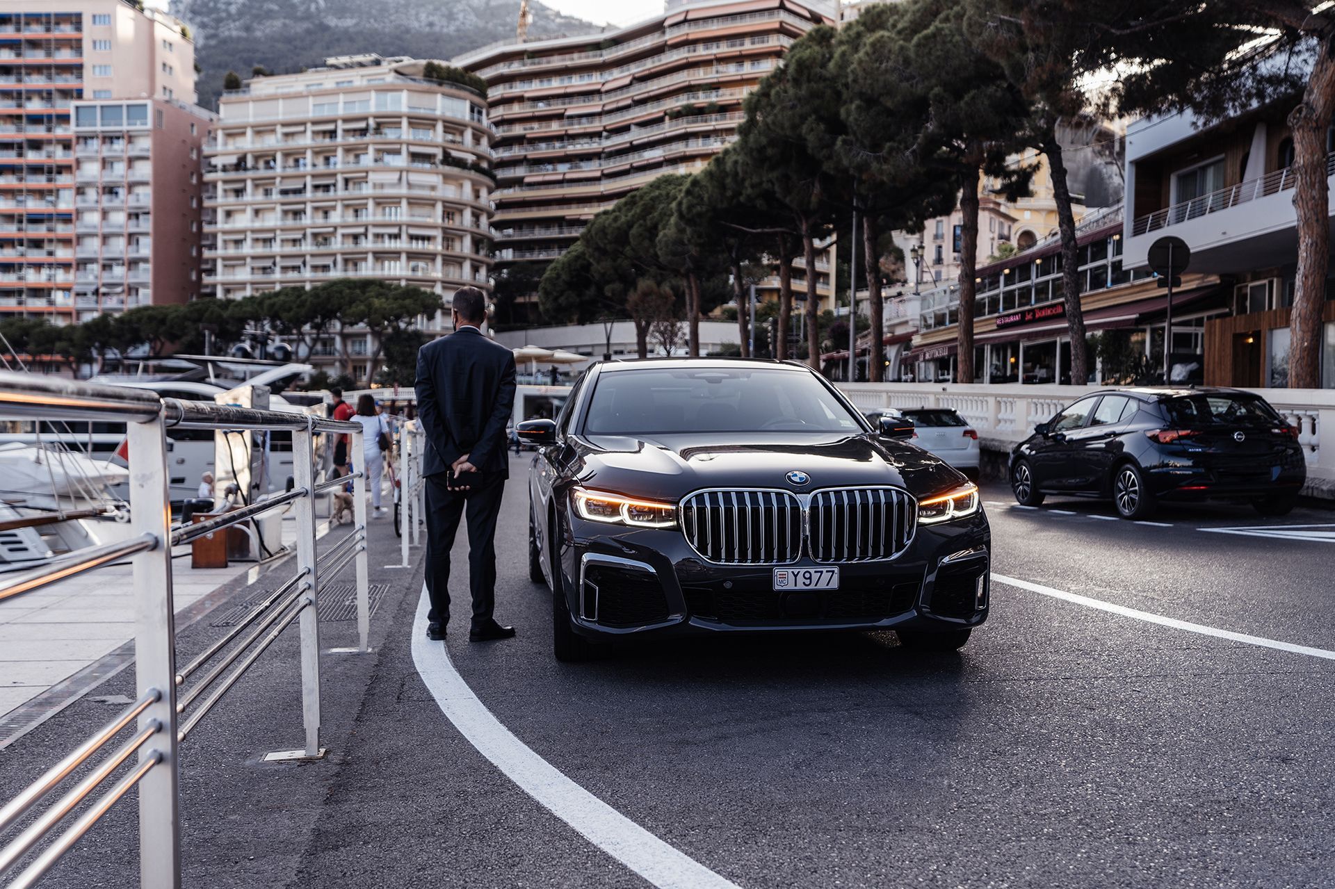 Chauffeur stands beside a black BMW SUV.