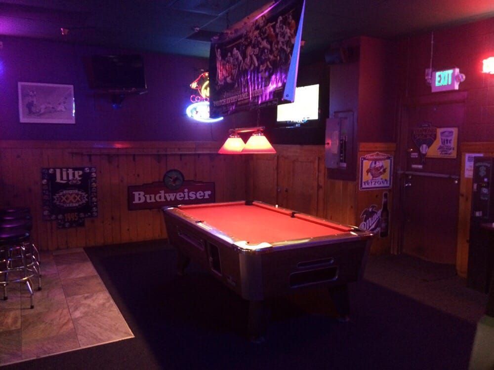 Back room with red-felt pool table and vintage neon signs