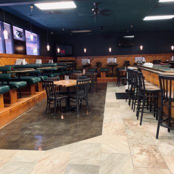 Bright daytime interior with green vinyl booths and dark bar top