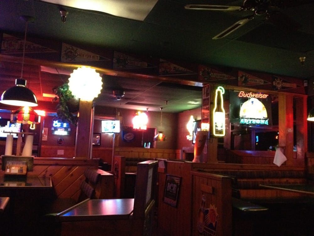 Dimly lit pub dining room at night with neon beer signs and sports pennants