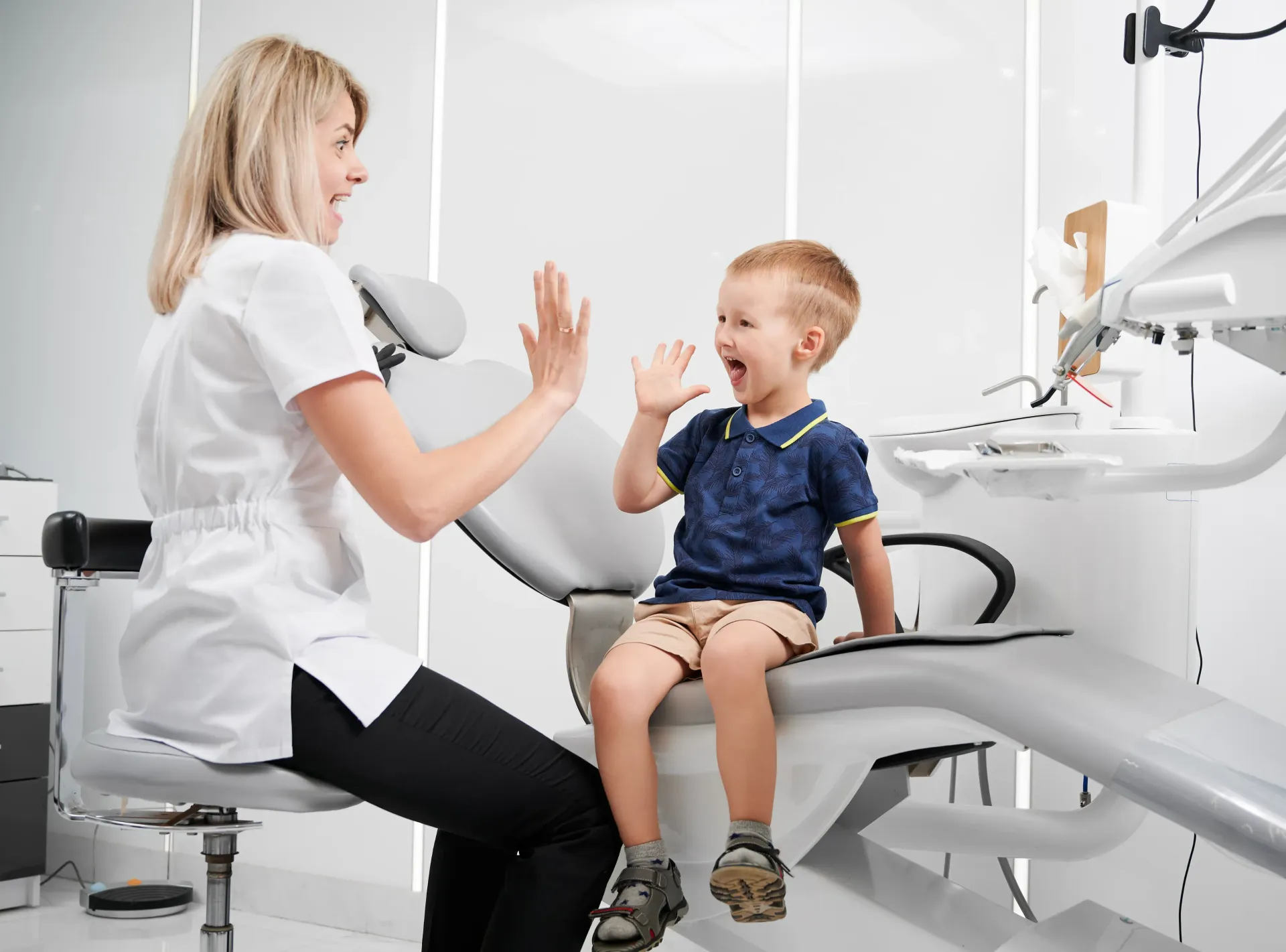 A woman is giving a child a high five in a dental office