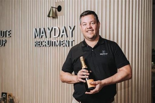 Man holding champagne bottle, smiling in front of