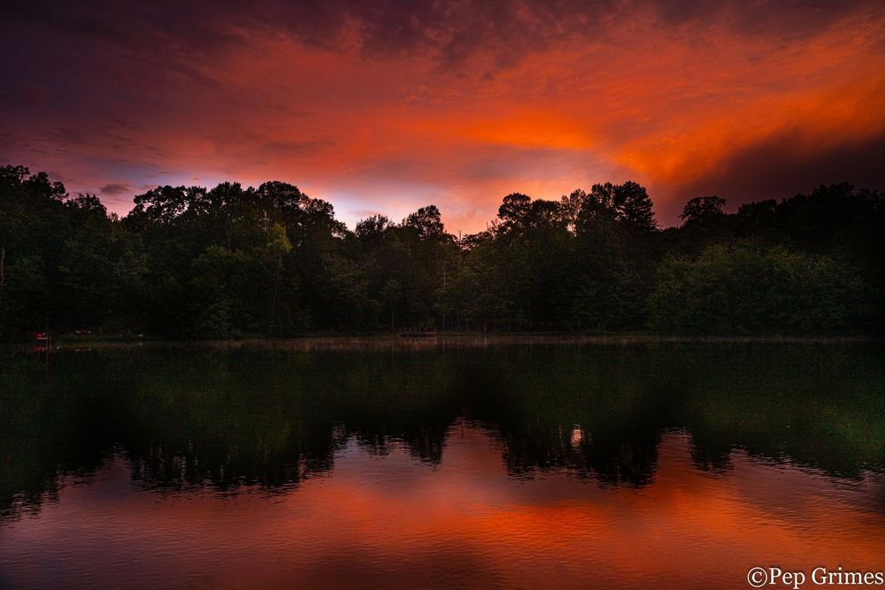 A sunset over a lake with trees in the background