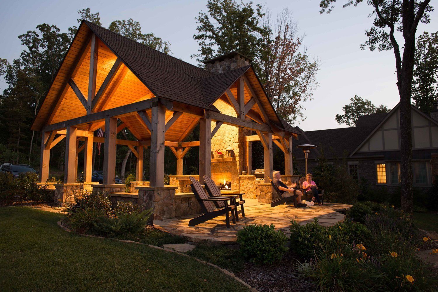 A group of people are sitting under a gazebo in front of a house.