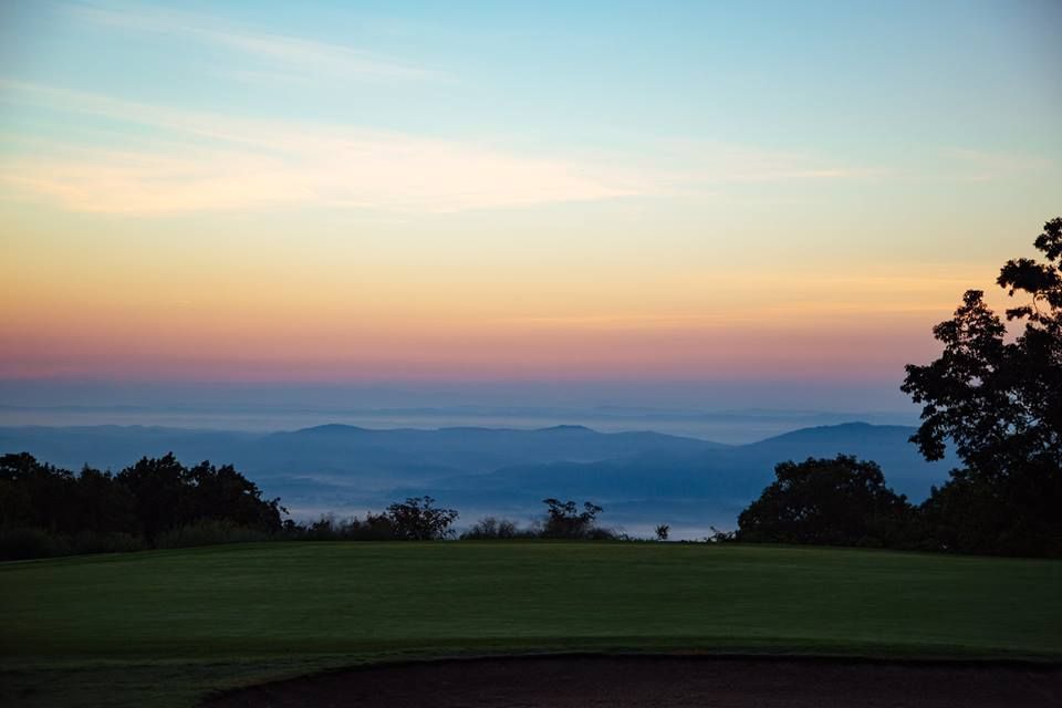 A sunset over a golf course with mountains in the background