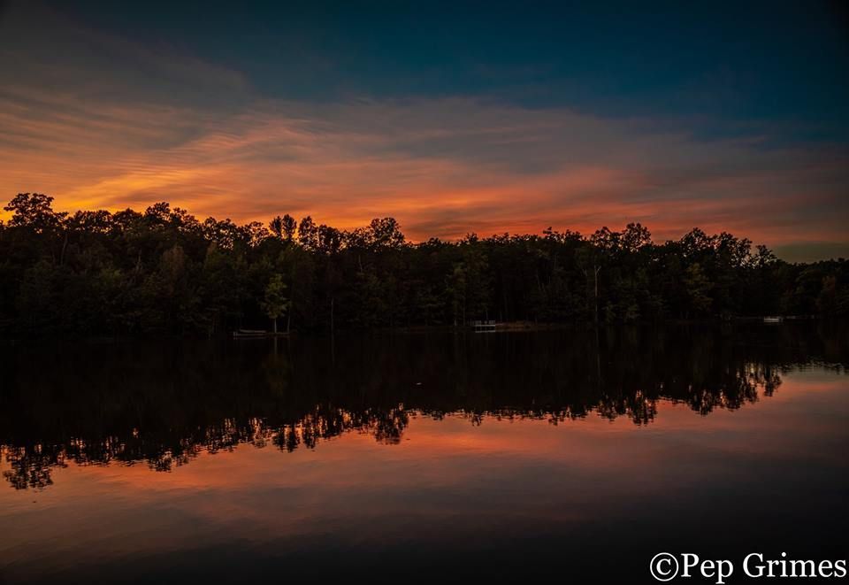 A sunset over a lake with trees in the background