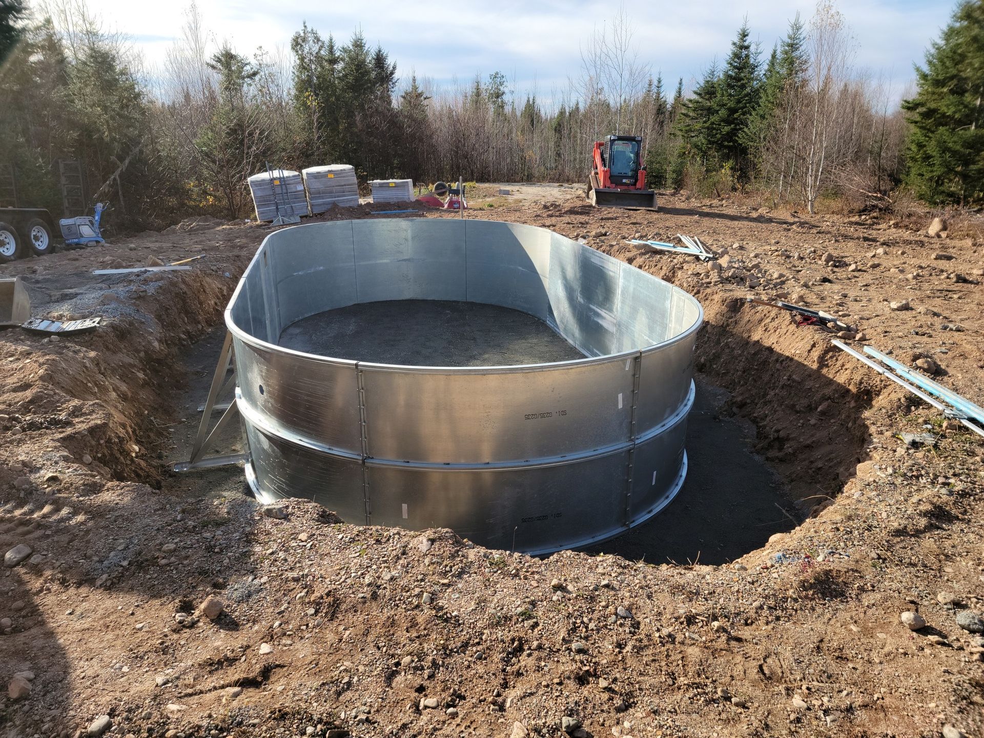 A large metal swimming pool is being built in a dirt field.