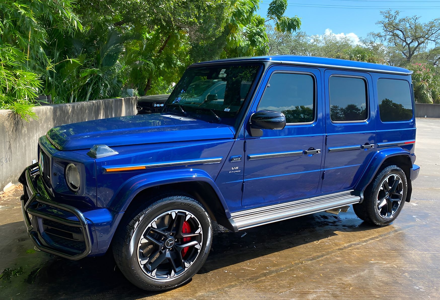 Blue Mercedes-Benz G-Class SUV parked outdoors; black wheels, tinted windows, and red brake calipers are visible.