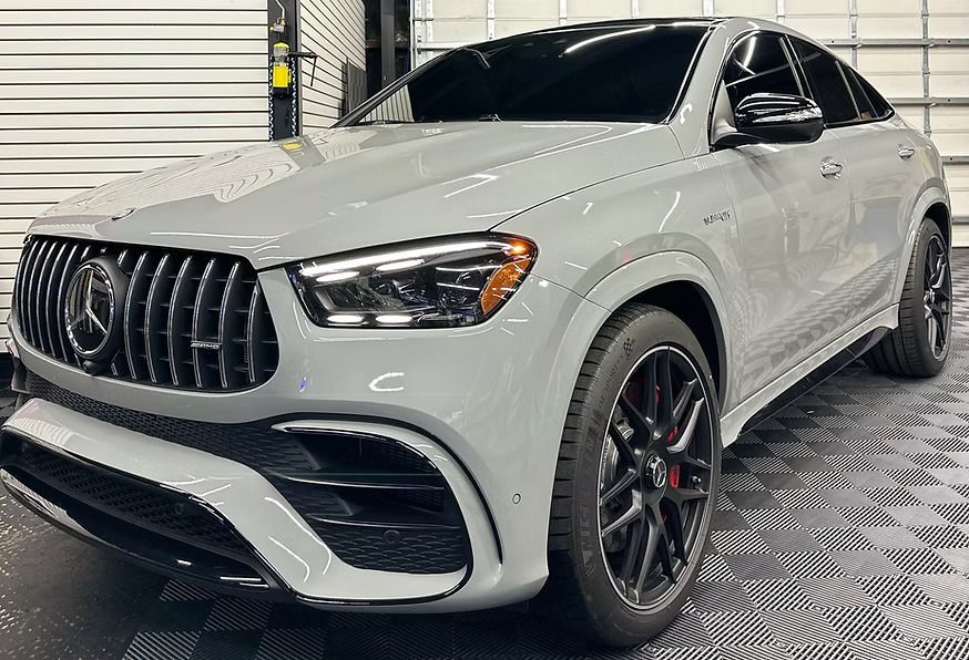 Gray Mercedes-AMG SUV coupe, front view. Black wheels and trim. Garage setting.
