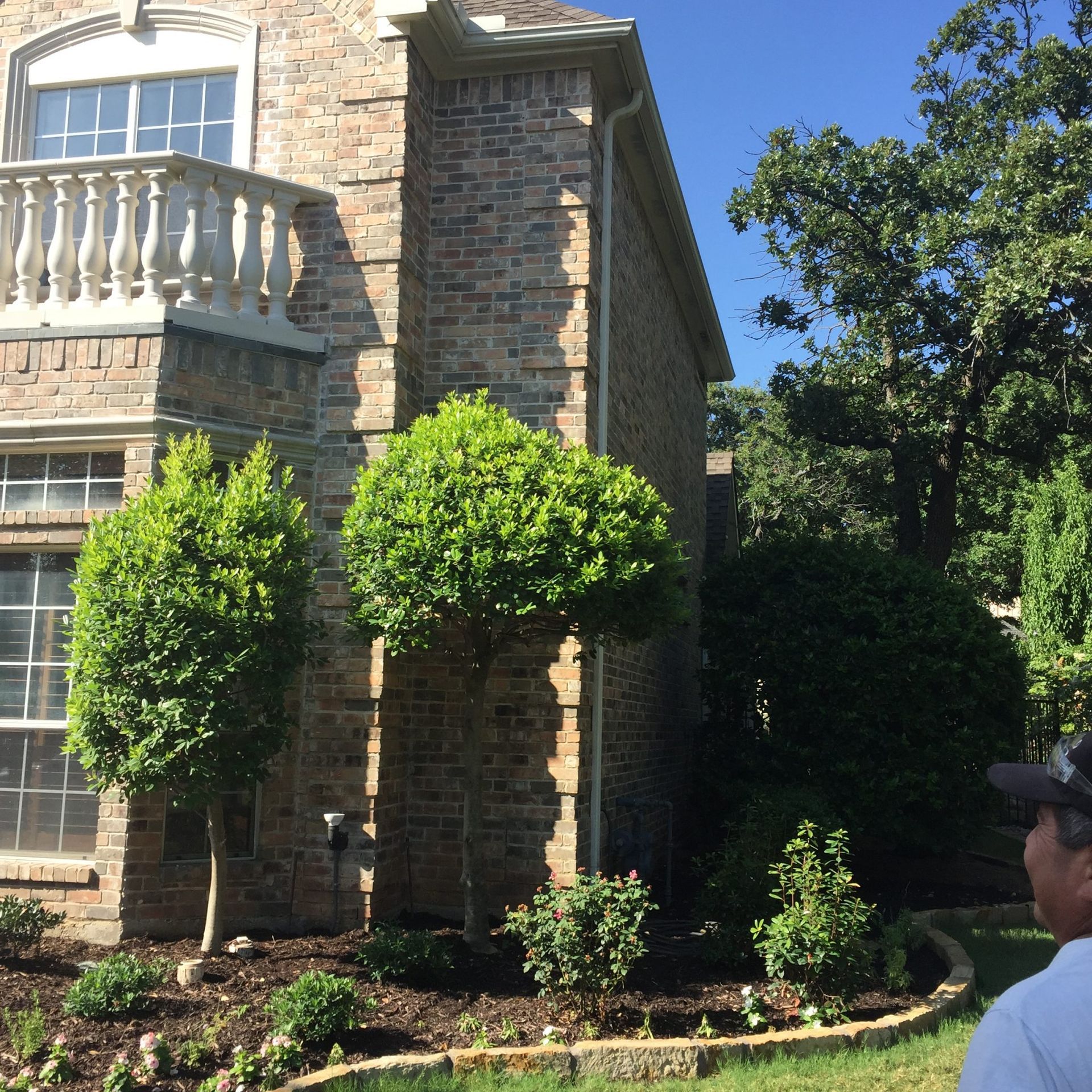 Stone house with manicured landscaping; person in the foreground.