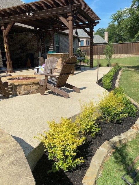Patio with fire pit, Adirondack chairs, and landscaping with yellow bushes.