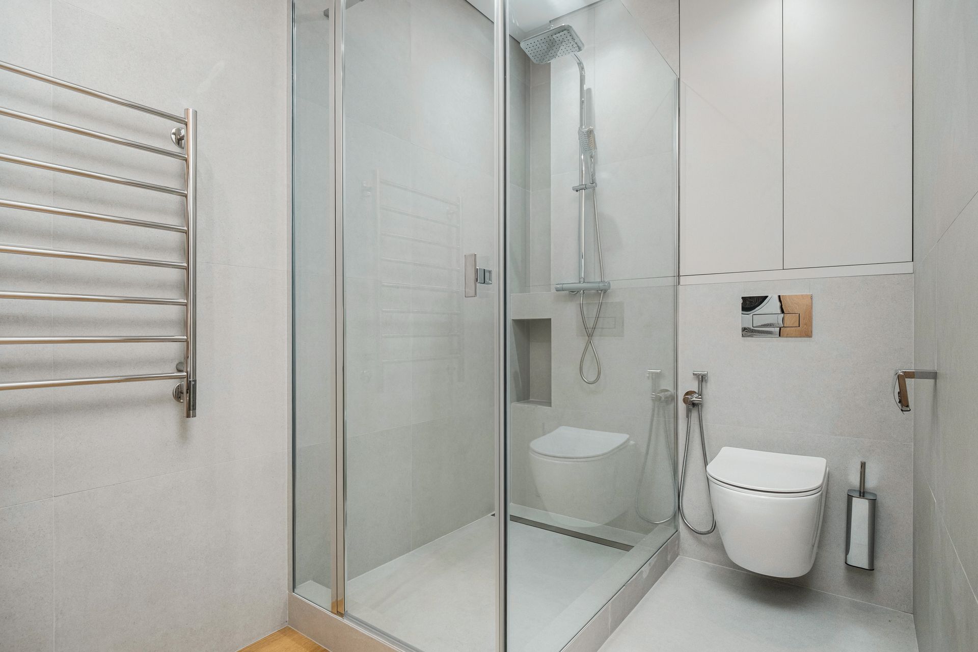 Modern white bathroom with glass shower, wall towel rail, and toilet