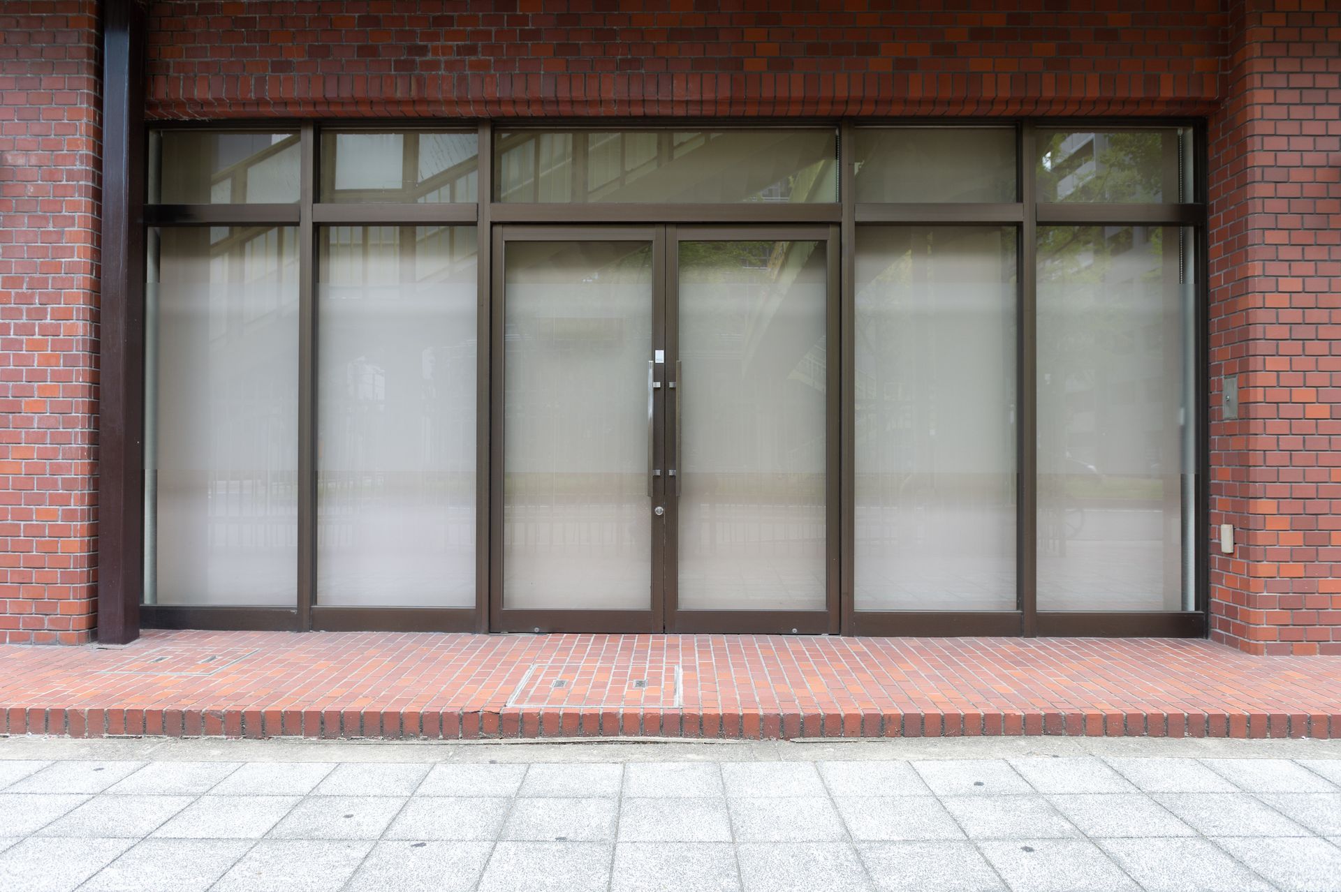Closed storefront with dark-framed glass doors and windows set in a brick building facade