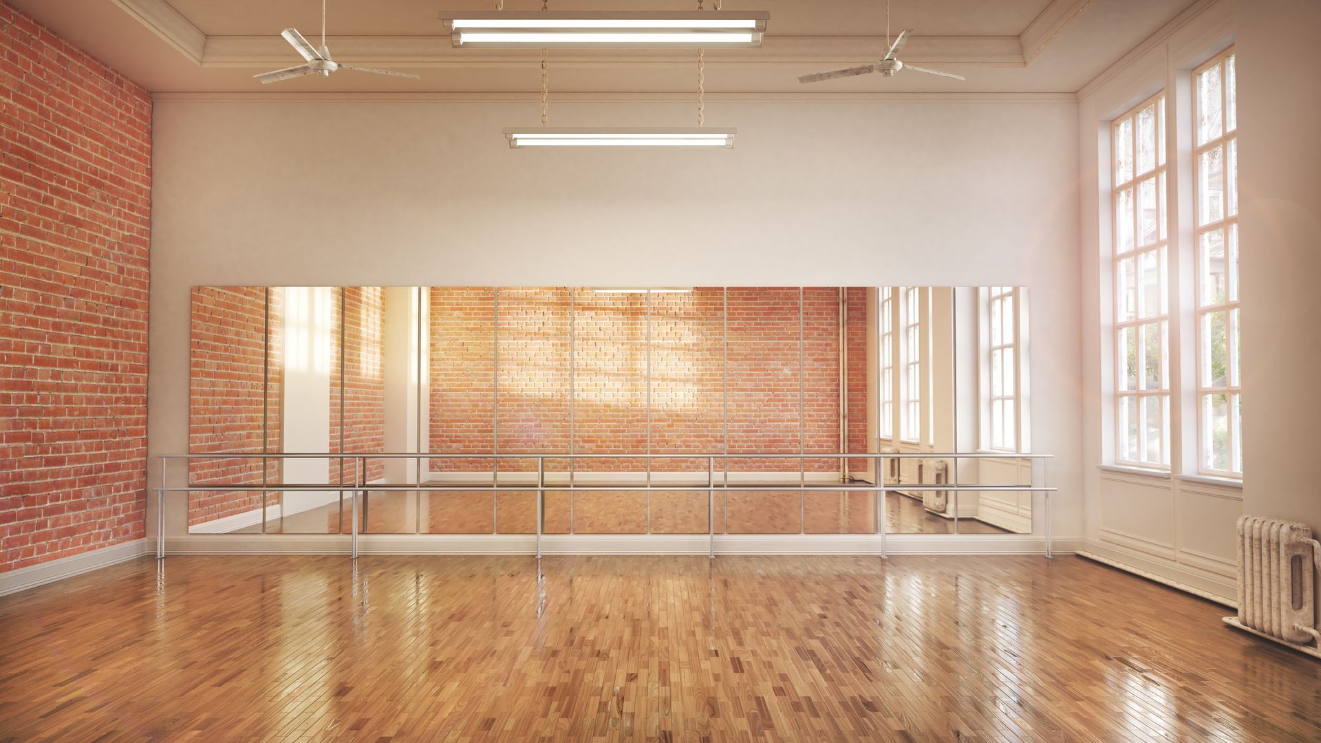 Bright empty dance studio with wooden floor, mirrored wall, ballet barre, and large windows.
