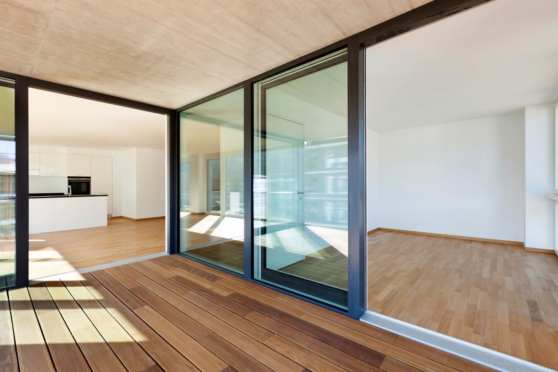 Modern open-plan interior with wood flooring and large glass sliding doors opening to a deck