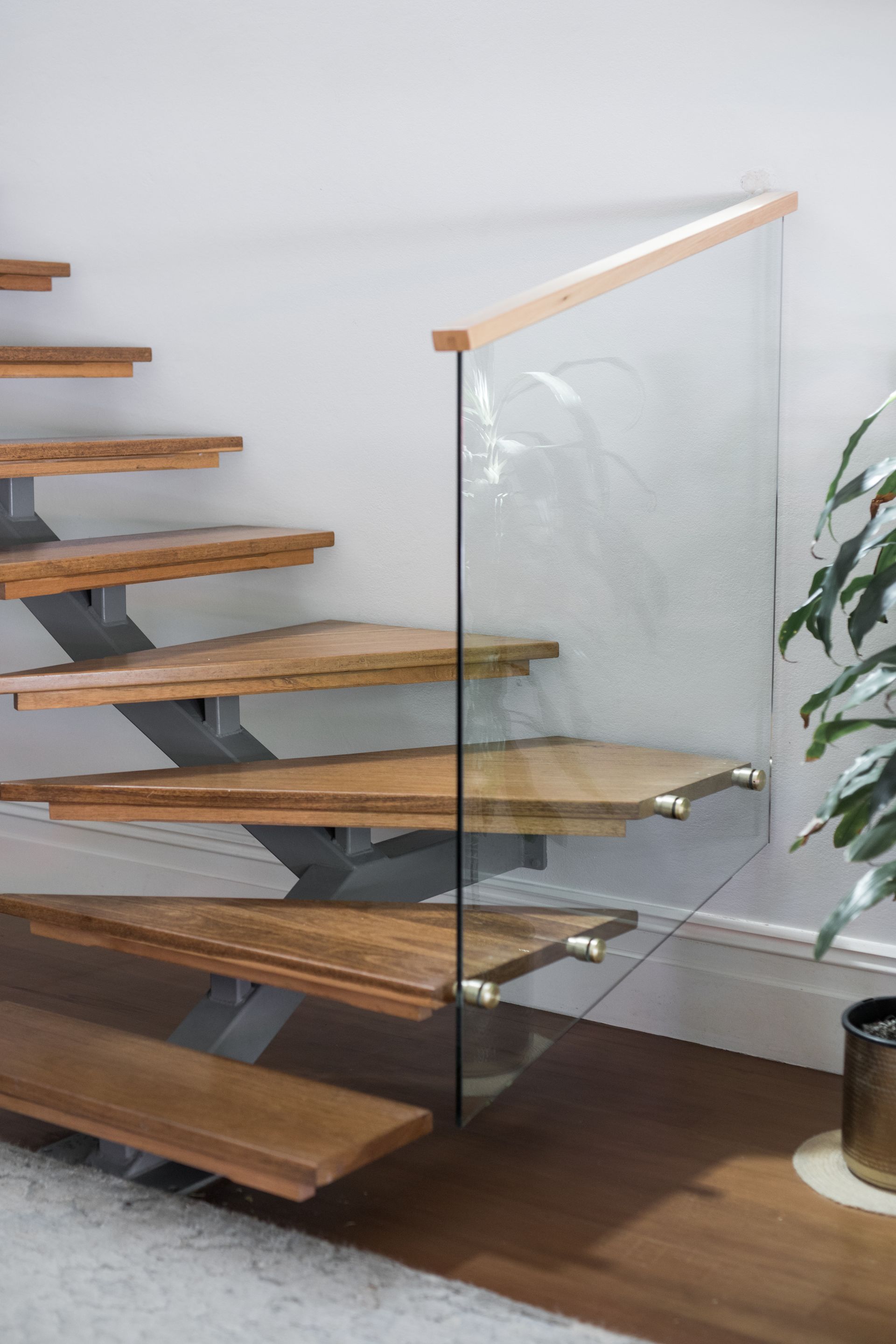 Floating wooden staircase with glass railing in a bright modern interior