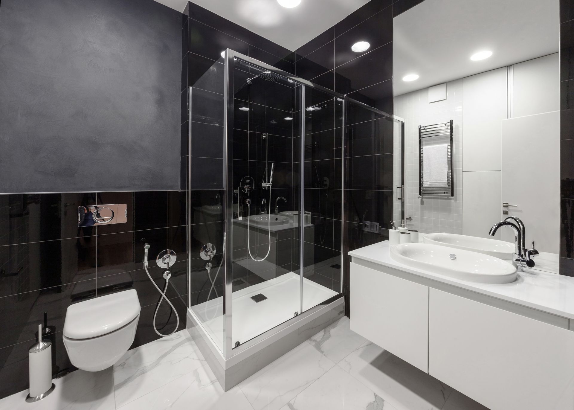 Modern black-and-white bathroom with glass shower, toilet, and vanity sink