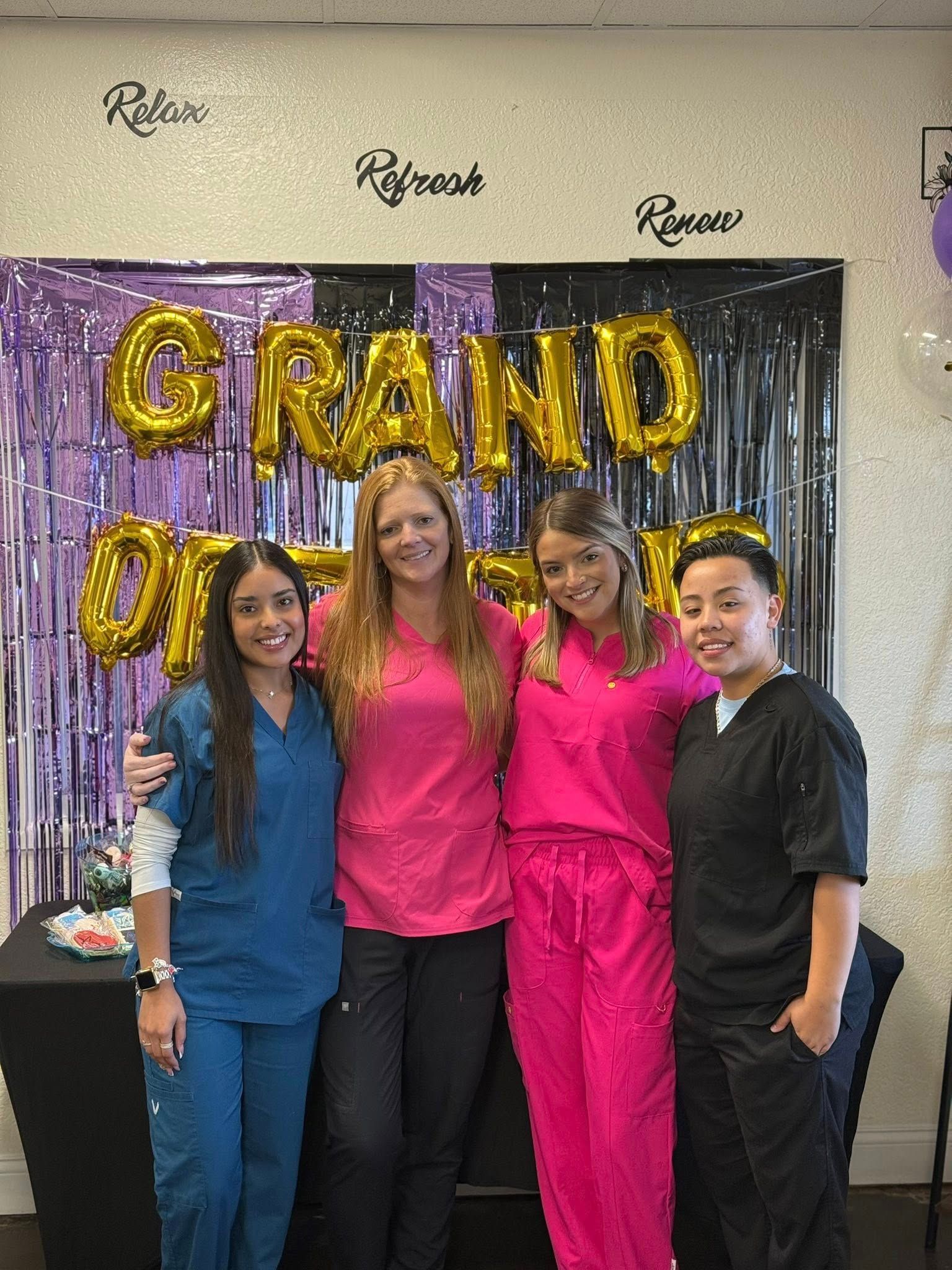 Four people in scrubs pose in front of