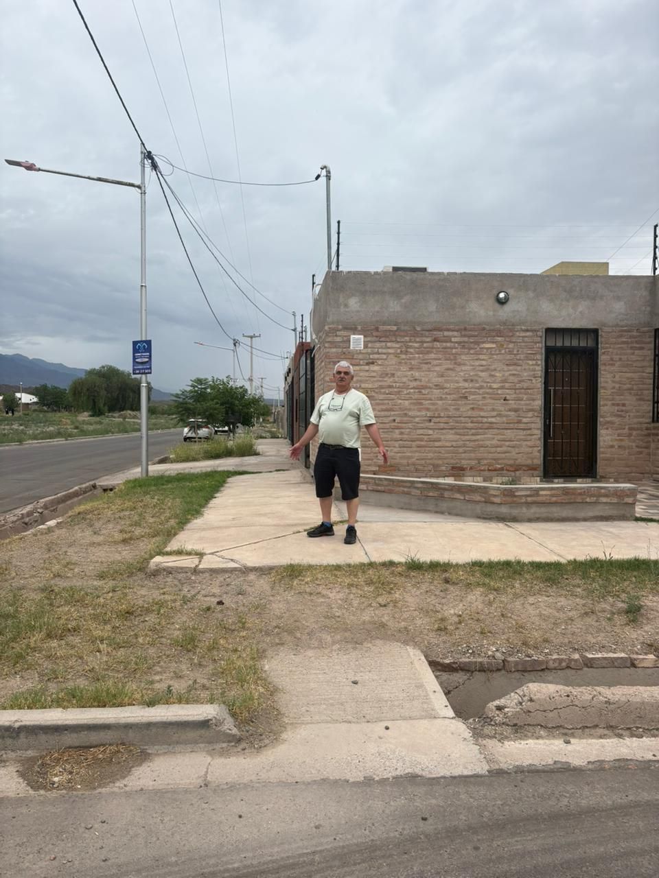 Un hombre está de pie en una acera frente a un edificio de ladrillo.