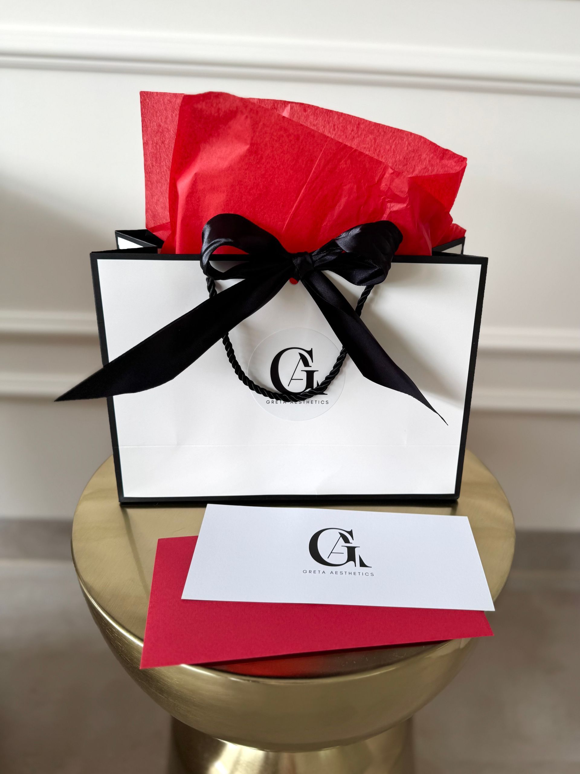 Geschenktüte mit schwarzer Schleife und rotem Seidenpapier auf einem goldenen Tisch;
