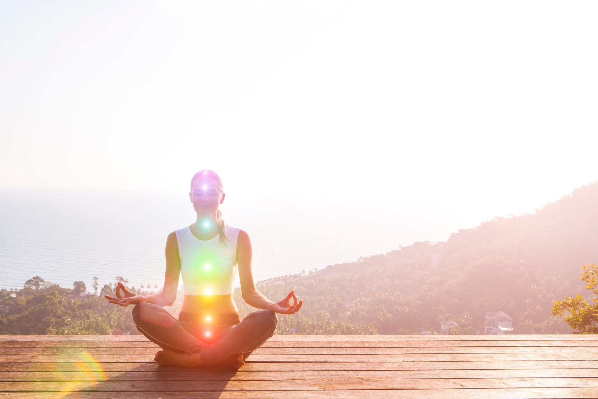 Woman meditating on wooden platform, with glowinchakra 