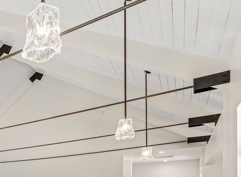 Modern white interior ceiling with black beams and hanging pendant lights