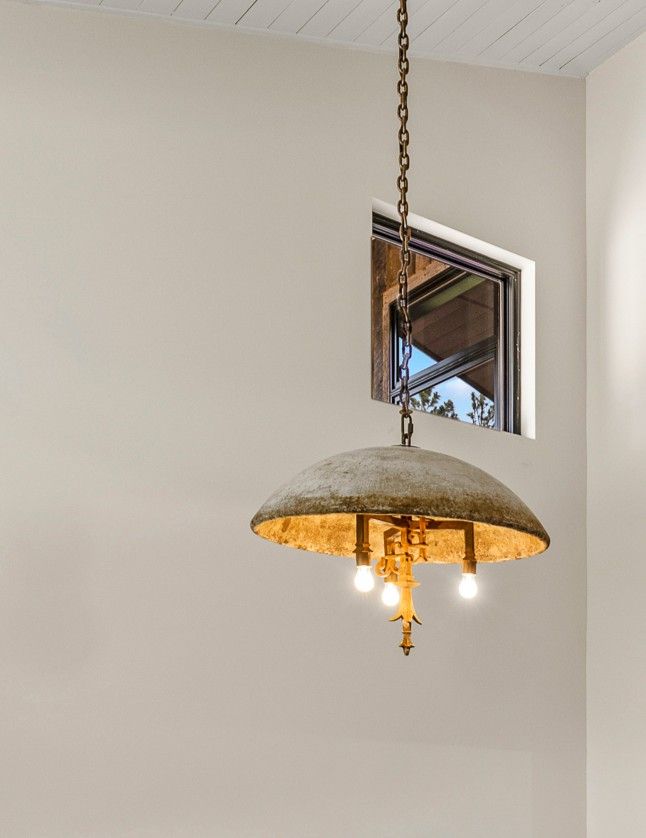 Hanging pendant light with a domed gray shade and warm bulbs in a beige room