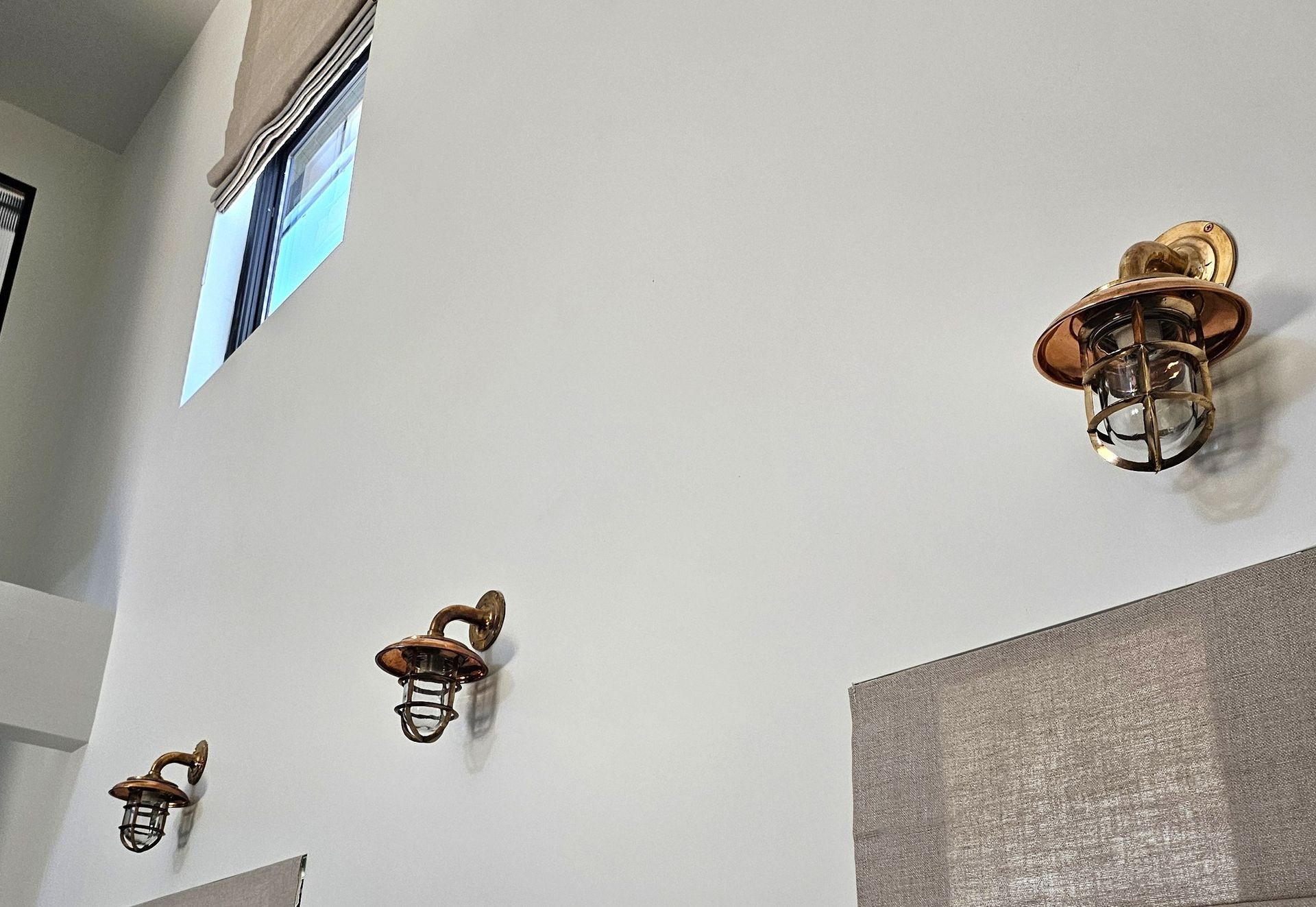 Interior white wall with three rustic wall sconces and a small high window