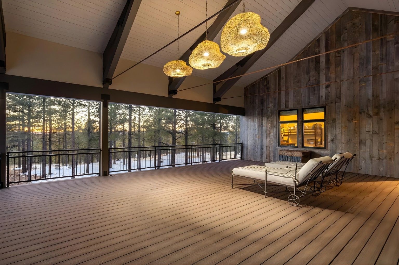 Modern loft living room with wood floors, large windows, pendant lights, and white chaise lounge