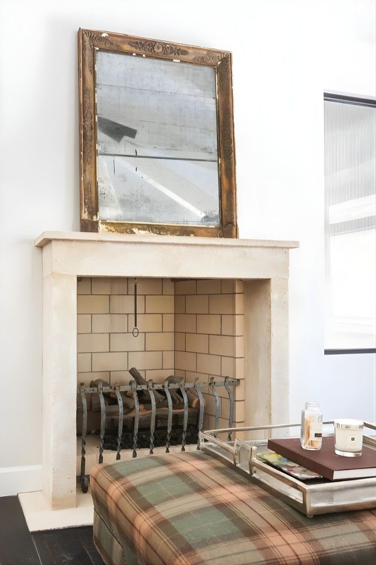 Plaid sofa in front of a white fireplace with a large mirror above and a tray on a coffee table.