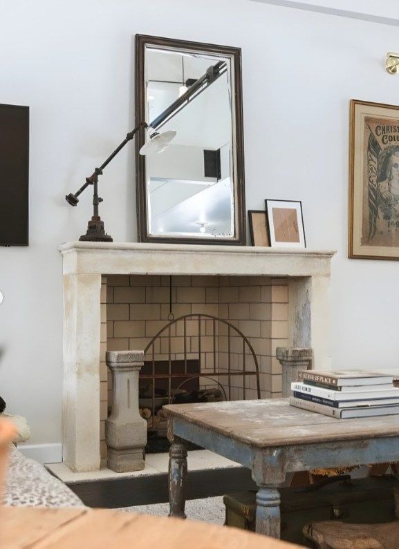 Cozy living room with white brick fireplace, mirror, artwork, and rustic coffee table
