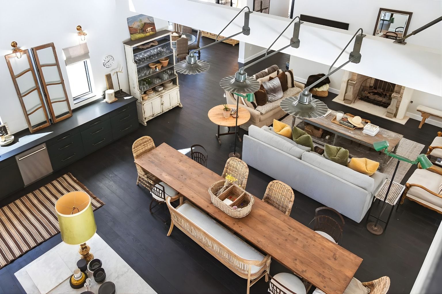 Top-down view of a modern open kitchen and dining area with a long wooden table and white sofa.