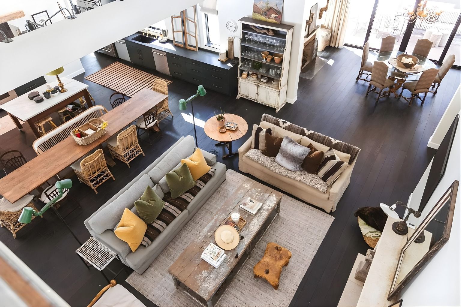 Modern living room showroom with sofas, chairs, rugs, and a dining area in the background
