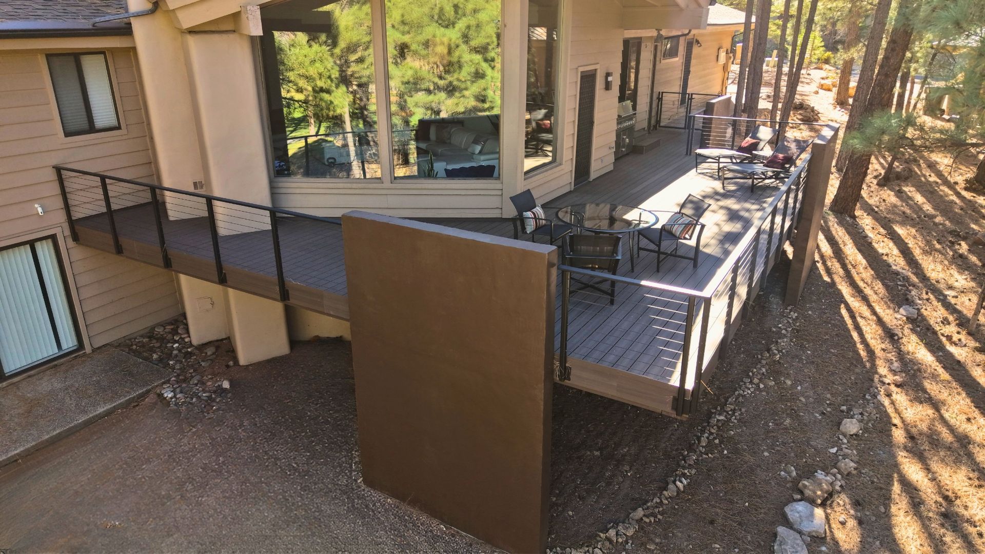 Outdoor apartment walkway with metal railing, stairs, and a brown privacy panel beside the building.