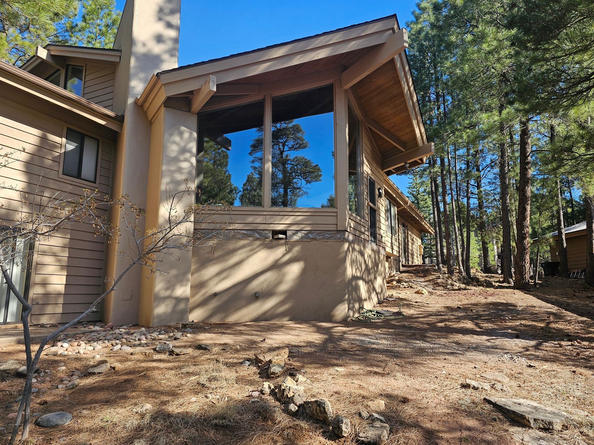 Stone house exterior with a covered porch and tall windows in a wooded setting