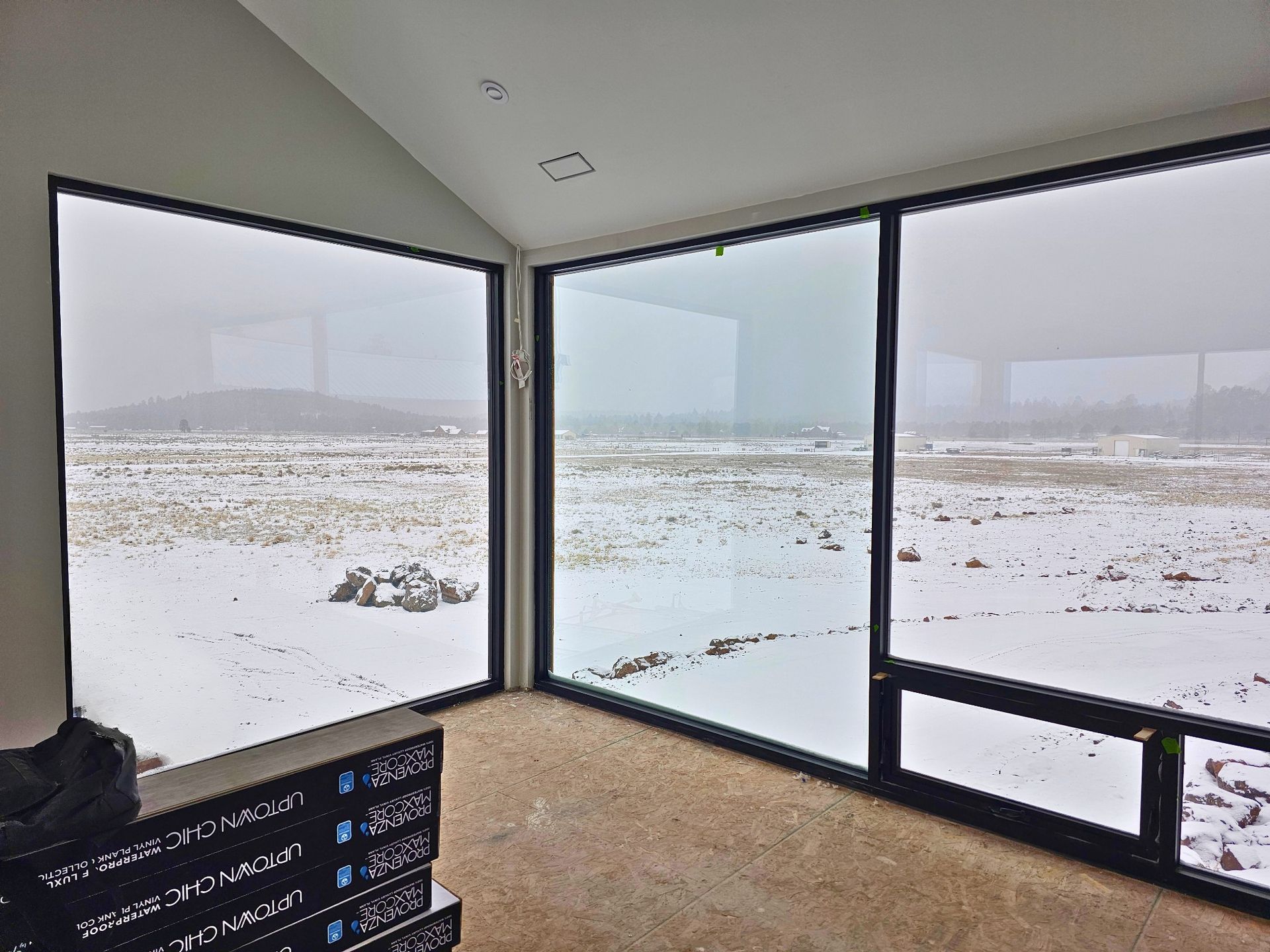 Minimalist room with floor-to-ceiling windows overlooking a snowy landscape
