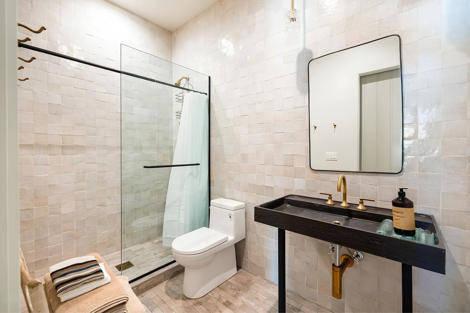 Modern bathroom with glass shower, white toilet, black vanity, and large mirror