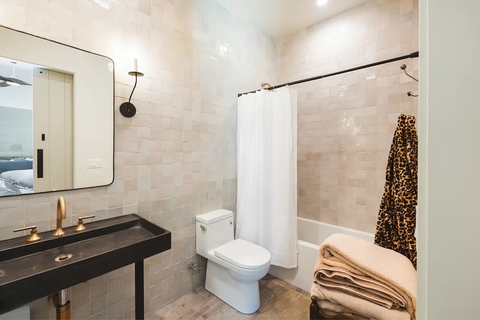 Modern bathroom with vanity, toilet, walk-in shower, and neutral tile walls.