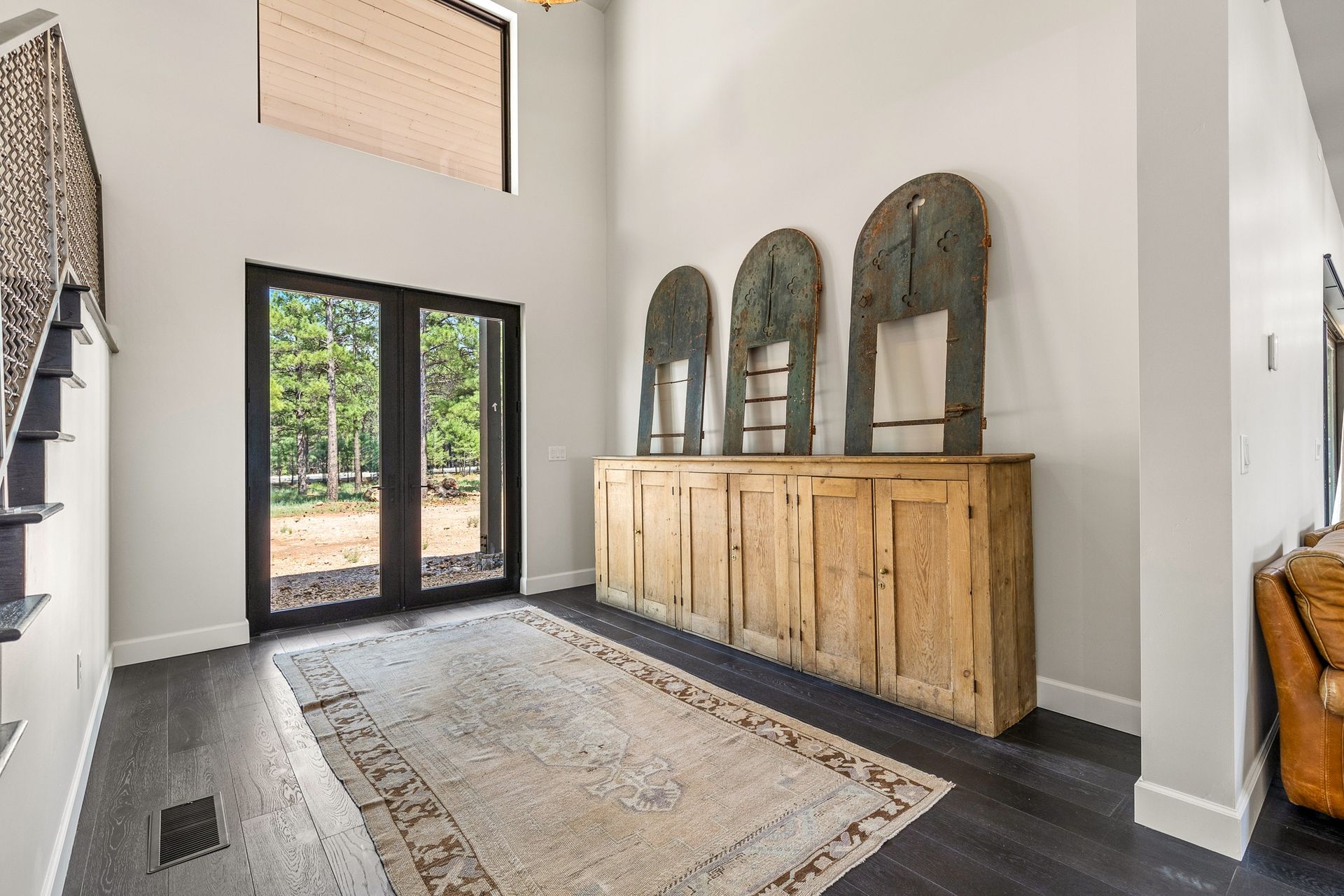 Bright entryway with black double doors, a long rug, and a wooden console with mirrors on top.