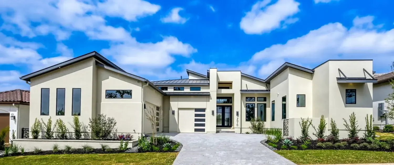 Modern white two-story house with a central walkway and landscaped front yard under a blue sky