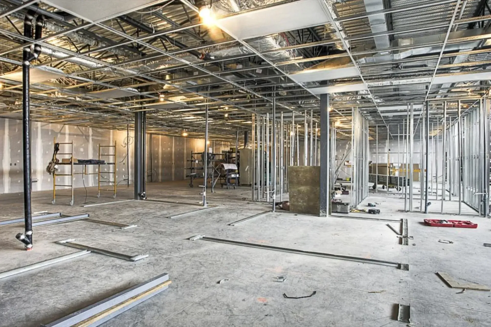 Unfinished building interior with exposed metal framing, wiring, and concrete floor under construction